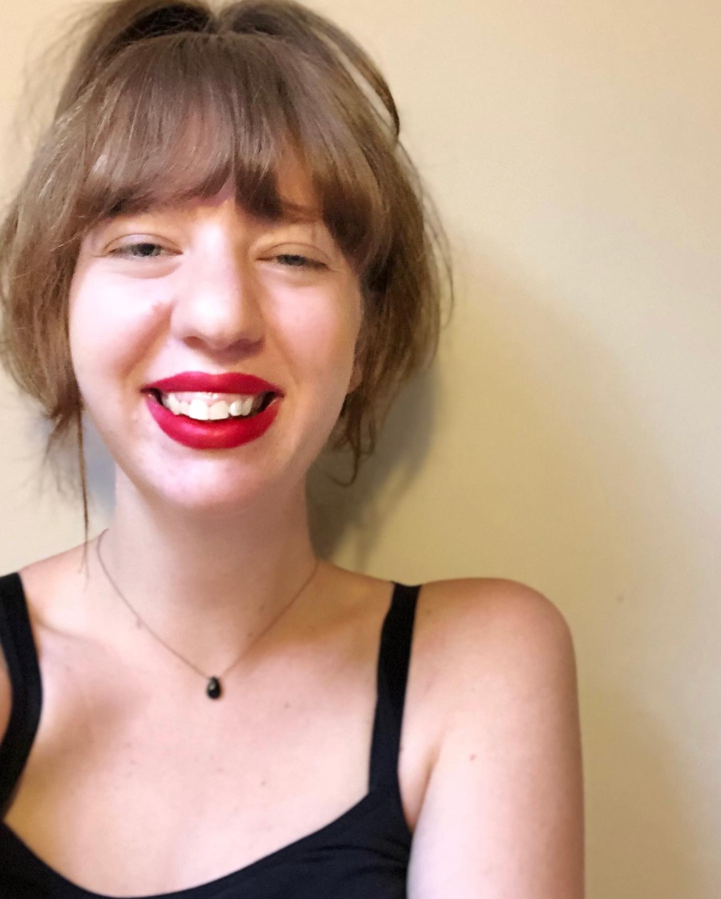 a picture of me smiling with a ponytail and red lipstick